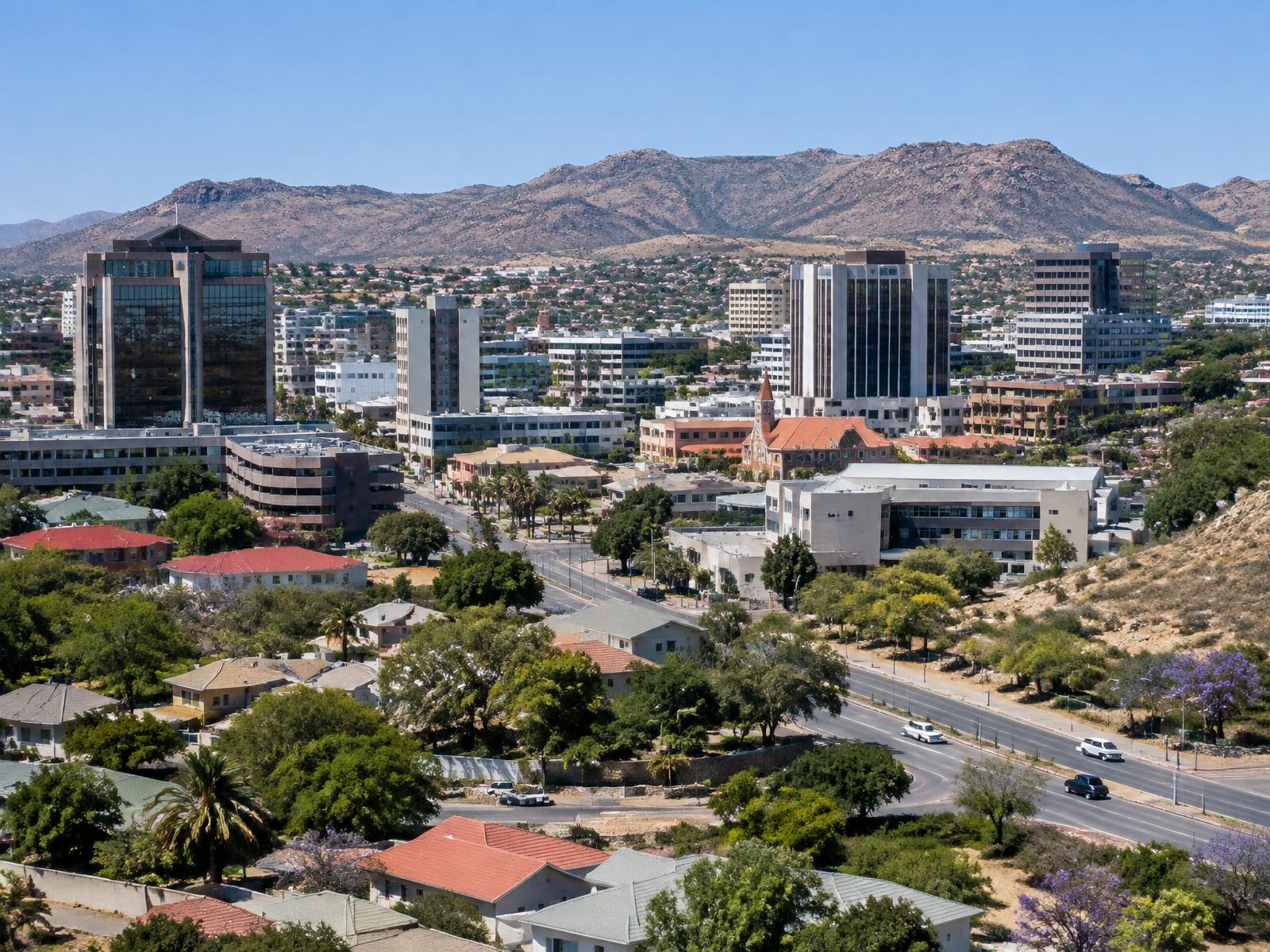 Generated editorial view of Windhoek, Namibia, showing commercial buildings, residential neighbourhoods and paved roads against dry highland hills; not an Afribiz project